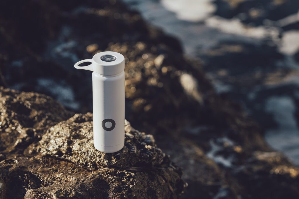 Reusable water bottle on rocks by the oceean