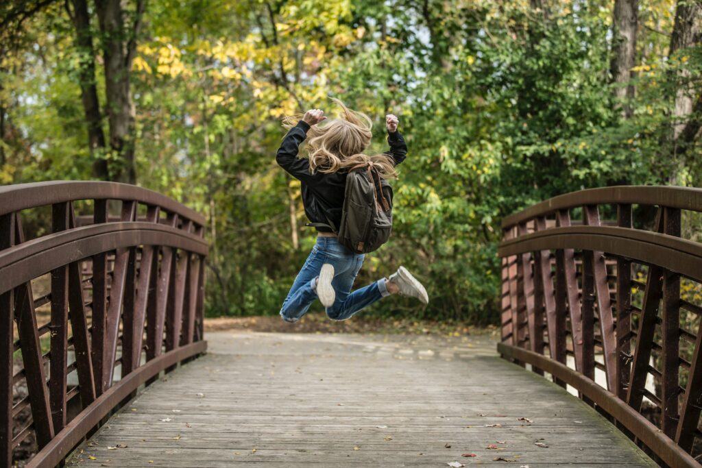 girl crossing bridge happily